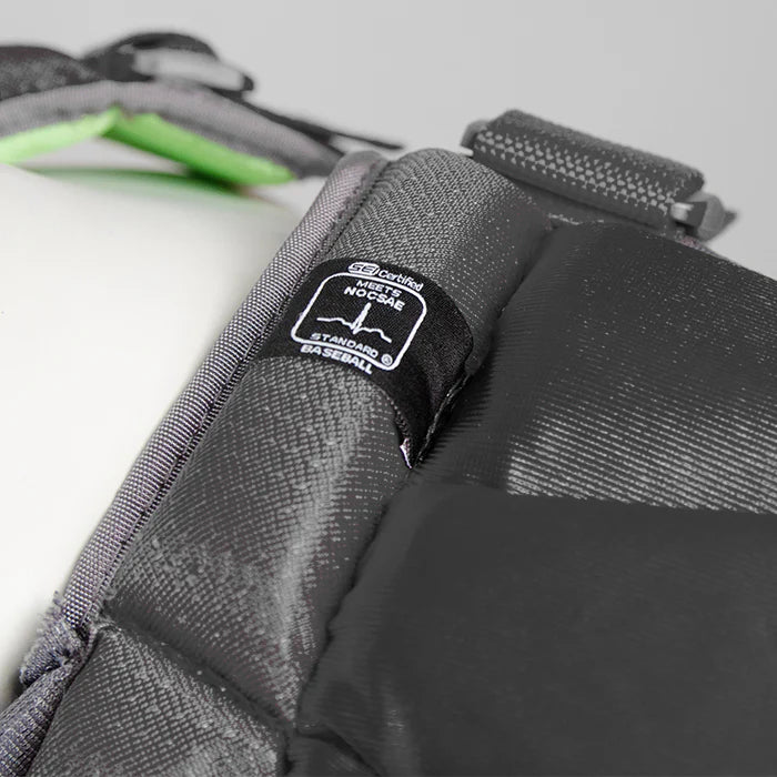 Close-up of the All Star System7 Axis Catcher's Kit (CKCC912S7X / CKCC1216S7X) by All Star, showing black padded helmet material with a "Certified NOCSAE" safety label, visible straps, and part of the green interior lining.