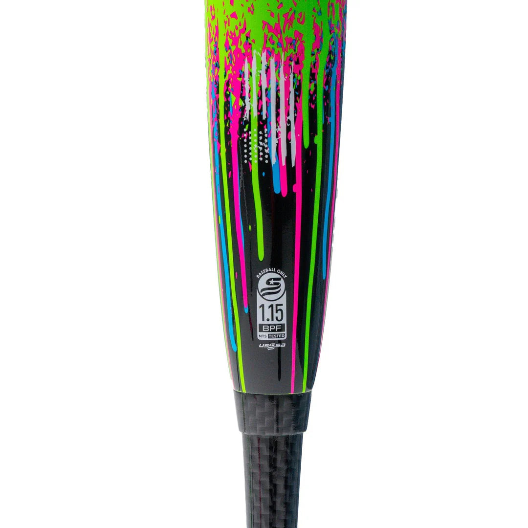 Close-up of the Soldier Sports 2026 Soldier Tank Double Wall (-8) 2 3/4" USSSA Baseball Bat, showcasing vibrant green, pink, blue, and white paint drips on black, double wall tech, and a certification label near the carbon fiber handle.