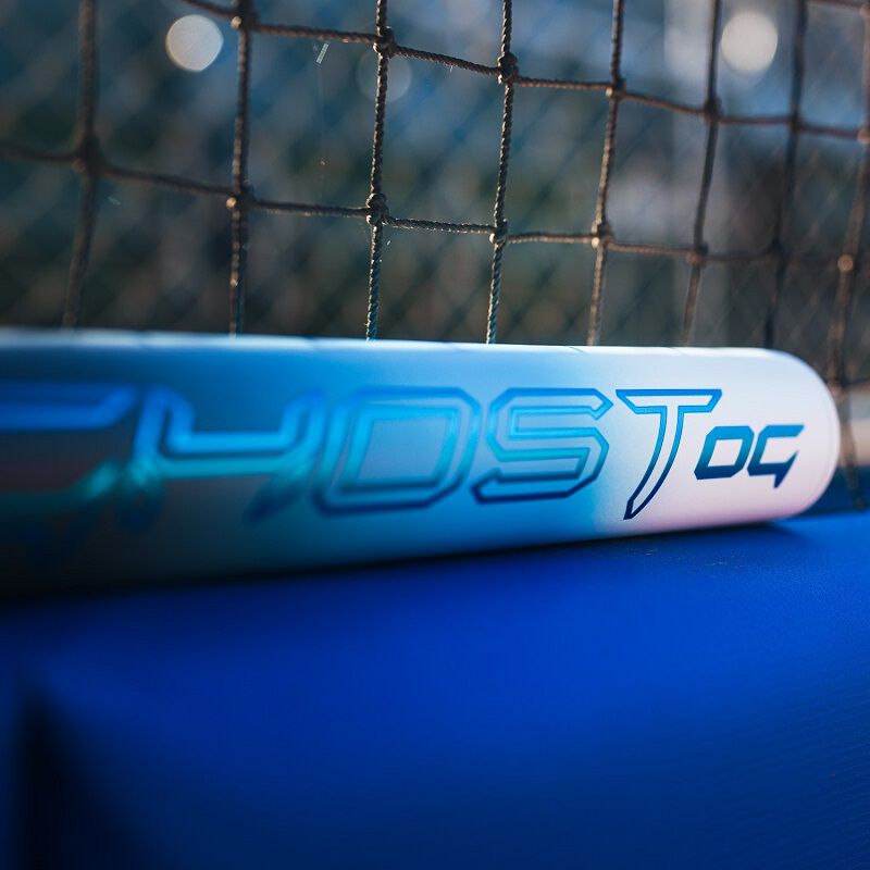 A close-up of the 2025 Easton Ghost OG (-11) Fastpitch Softball Bat (EFP5GHOG11) by Easton, featuring Double Barrel construction, resting on a blue surface with a blurred net in the background.