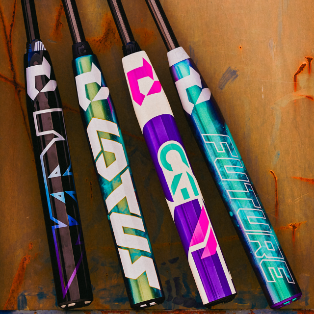 Four vibrantly colored baseball bats with bold, geometric designs and futuristic lettering lean against a textured, tan and orange wall. Each bat features different colors and patterns.