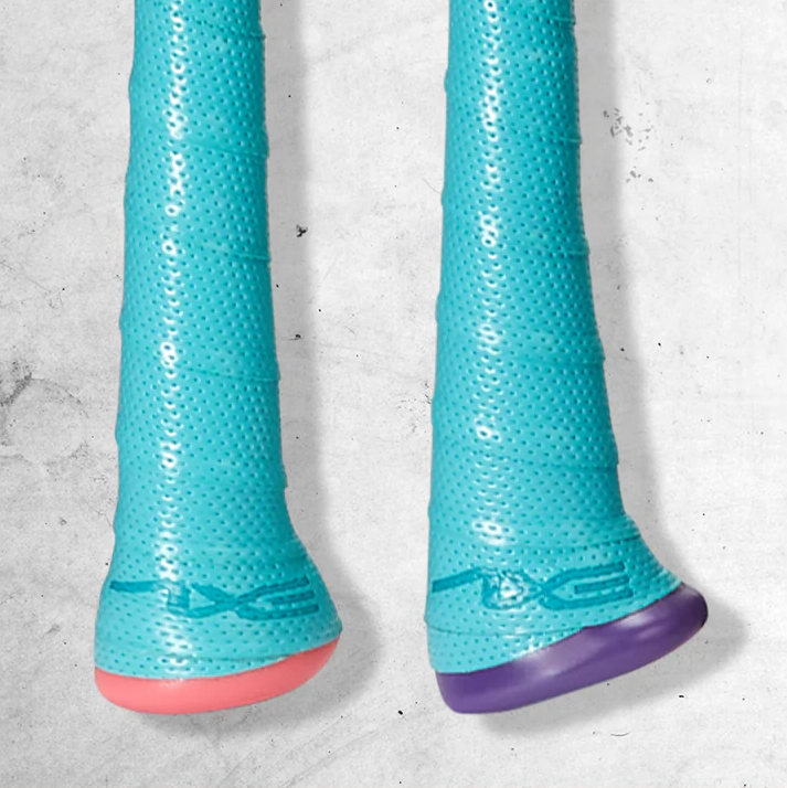 Two blue textured grips with perforated surfaces, each ending in a flared bottom—one with a pink base and one with a purple base—lying side by side on a gray, textured background.