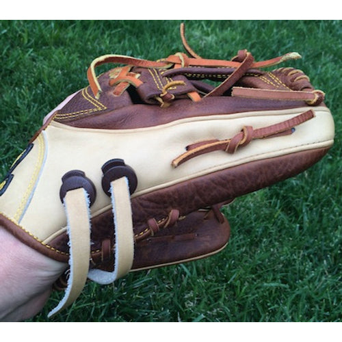 A close-up of a person’s hand wearing an All Star baseball glove secured with the All Star GloveLock (4 Pack): GL-4PACK on a grassy field.