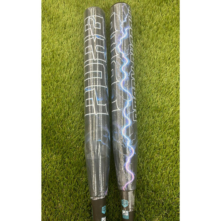 Two Pure Sports bats, including the 2025 Pure Storm Shadow 13″ Balanced USA Slowpitch Softball Bat (5147M91B) with a black and silver design and white lightning bolts, lie side by side on green artificial grass.