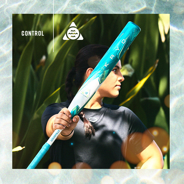 A person in a black shirt holds a teal and white baseball bat labeled KAYO and CONTROL, posing confidently outdoors with green foliage in the background.