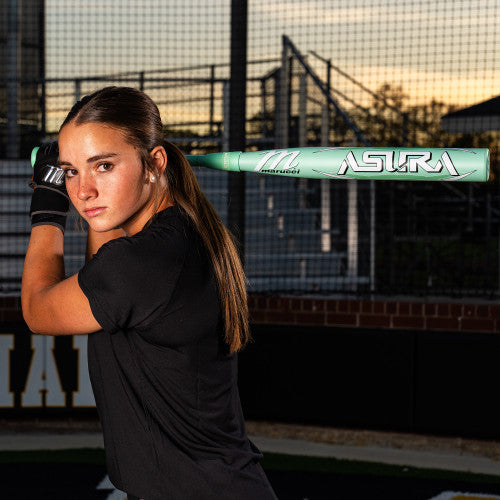 A woman holding the 2025 Marucci ASURA (-8) Fastpitch Softball Bat (MFPAS8) by Marucci, featuring innovative Gap Sync barrel technology.