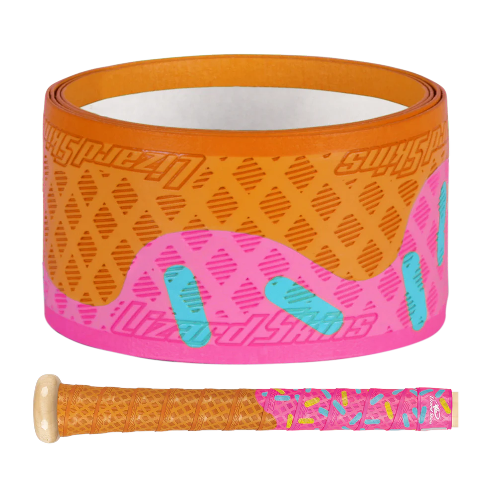 The Lizard Skins DSP Ultra Outburst 1.1mm Bat Grip in Pink Scoop features a donut-inspired tan base, pink top, and blue sprinkles. Made by Lizard Skins from durable polymer, it's shown both rolled up and wrapped on a bat handle.