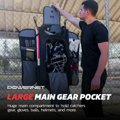 A man stands next to an open PowerNet Optimus Catcher's Gear Bag (B013-BK) hanging on a fence, showing a spacious compartment with catcher’s gear, gloves, balls, and a helmet. Text: PowerNet LARGE MAIN GEAR POCKET.