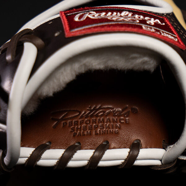 Close-up of the inside of a Rawlings baseball glove, showing the leather palm lining with the text Heart of the Hide Performance Sheepskin Palm Lining embossed on it. Brown leather laces are visible.
