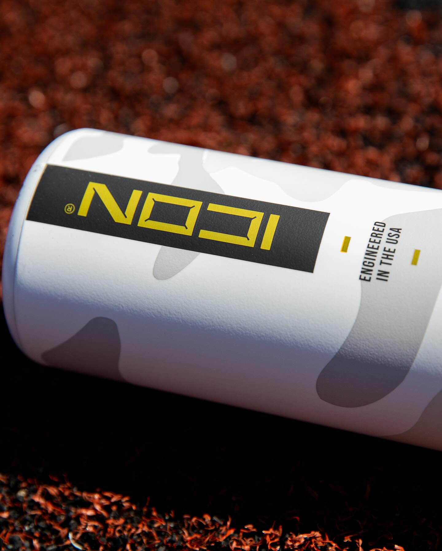 A close-up of a white Rawlings can with gray camo and a black label reading "ICON" in bold yellow, inspired by the 2025 Rawlings Icon (-5) 2 3/4" USSSA Baseball Bat: RUT5I5, a top carbon composite bat. Engineered in the USA appears below.