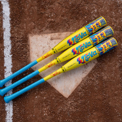Three blue and yellow 2026 Victus Nova Lit (-8) USSSA baseball bats by Victus rest side by side on home plate, standing out on the dirt field.