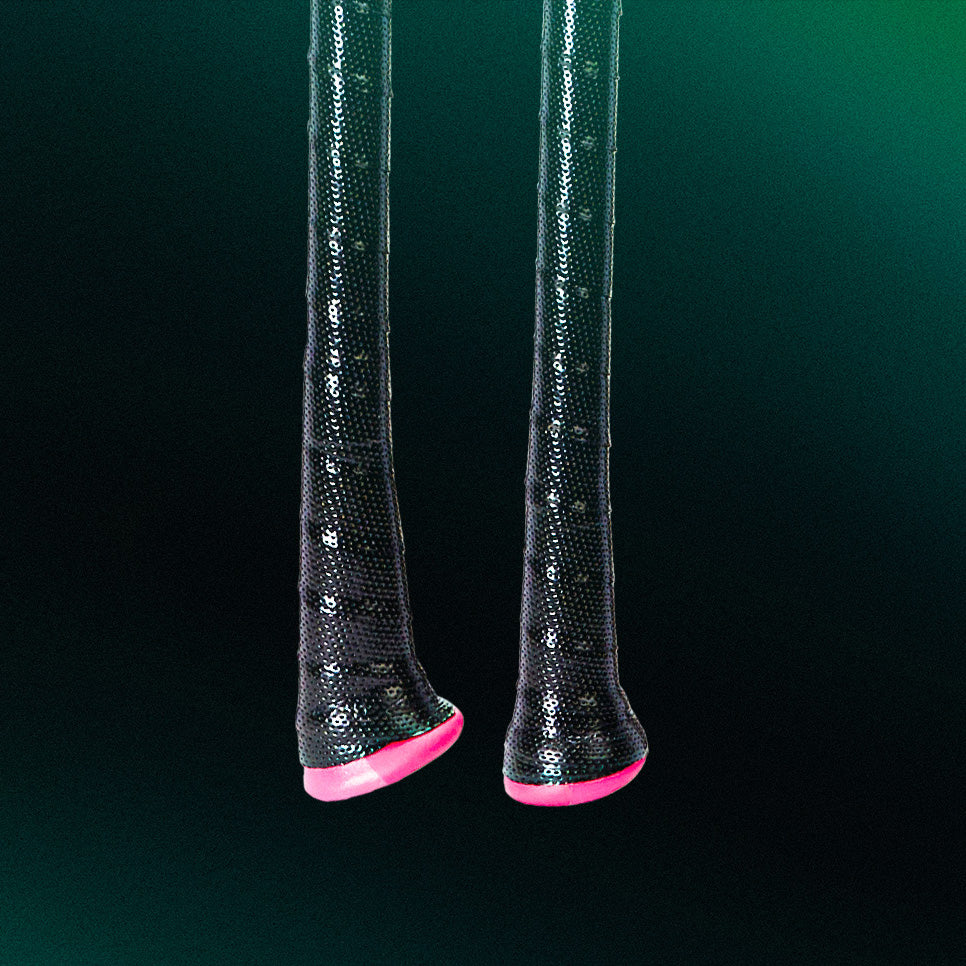 Two elongated black sequin-covered objects with bright pink tips hang vertically against a dark green gradient background.