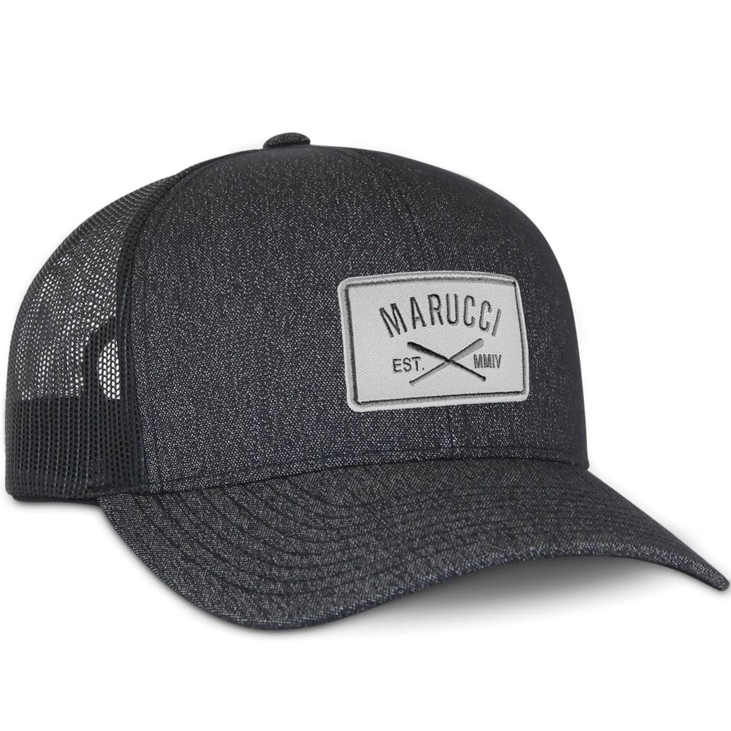 The Marucci Cross Patch Snapback Hat (MAHTTRPCS) is a black trucker mesh baseball cap with a light gray front patch displaying the Marucci logo above crossed bats and "EST. MMIV," plus an adjustable snapback closure.