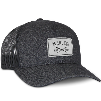 The Marucci Cross Patch Snapback Hat (MAHTTRPCS) is a black trucker mesh baseball cap with a light gray front patch displaying the Marucci logo above crossed bats and "EST. MMIV," plus an adjustable snapback closure.