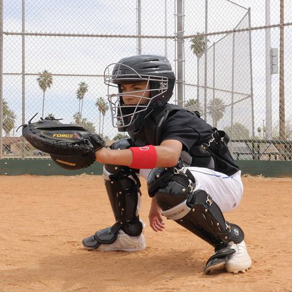 A boy wearing a helmet and knee pads, holding a baseball glove, and sporting Force3 Catcher's Leg Guards with Dupont Kevlar: BC8 by Force3 as part of his protective sports gear.