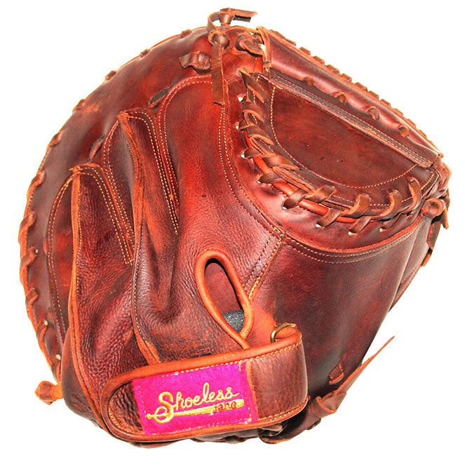 A brown leather Shoeless Joe 32" Fastpitch Catcher's Mitt (3200FPCM) features visible stitching and a maroon wrist strap label reading "Shoeless" in yellow.