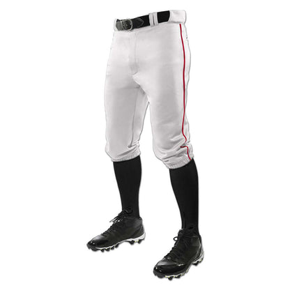 A person waist down in Champro Sports Youth Triple Crown Knicker Baseball Pants with red piping (BP101Y), a black belt, black knee-high socks, and black cleats, shown against a white background.