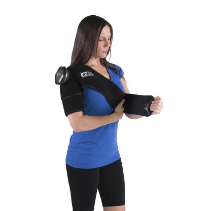 A woman in a blue shirt wears the Bownet ICE20 Single Shoulder Ice Compression Wrap (ICE-Shoulder), securing the strap around her upper arm. The neoprene wrap with a refillable ice bag provides targeted shoulder relief.