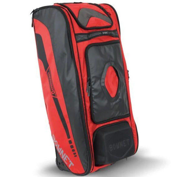 The Bownet Commander Wheeled Catcher's Bag (BN-COMMANDER BAG) is a large, rectangular red and black bag with multiple compartments, zippers, sturdy handles, and Bownet branding on the side and front for easy transport of baseball equipment.
