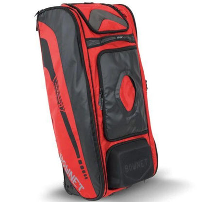 The Bownet Commander Wheeled Catcher's Bag (BN-COMMANDER BAG) is a large, rectangular red and black bag with multiple compartments, zippers, sturdy handles, and Bownet branding on the side and front for easy transport of baseball equipment.