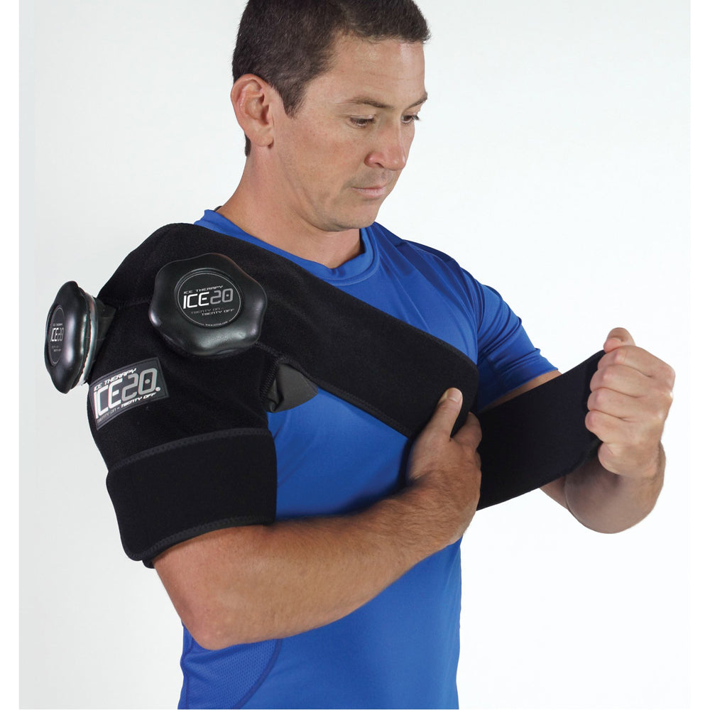 A man in a blue shirt adjusts a black Bownet ICE20 Double Shoulder Ice Compression Wrap (ICE-Dbl-Shoulder) with a refillable ice bag on his right arm and shoulder.