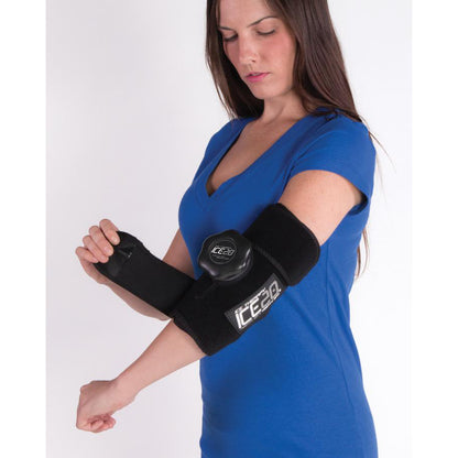 A woman in a blue shirt adjusts a Bownet ICE20 Elbow / Small Knee Ice Compression Wrap (ICE-ELBOW-SM KNEE) on her left arm for ice therapy or injury support, with a plain white background.