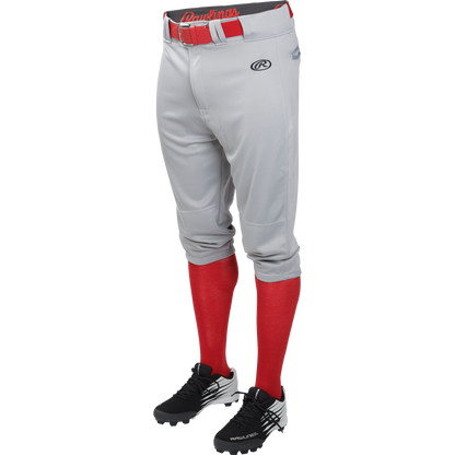 A mannequin wears Rawlings Adult Launch Knicker Baseball Pants (LNCHKP) in gray with a visible Rawlings logo, paired with a red belt, red knee-high socks, and black cleats featuring white accents.