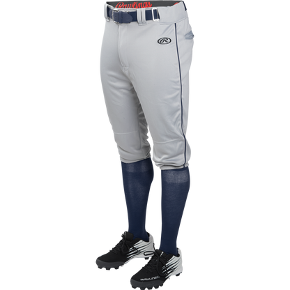 A person wears Rawlings Adult Launch Knicker Baseball Pants with Piping (Blue Grey/Navy), styled with a blue belt, blue knee-high socks, and black and white cleats, shown waist down against a plain background.