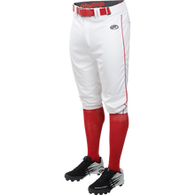A person is wearing Rawlings Youth Launch Knicker Baseball Pants with red piping, a red belt, red socks, and black cleats. Only the lower body is visible.