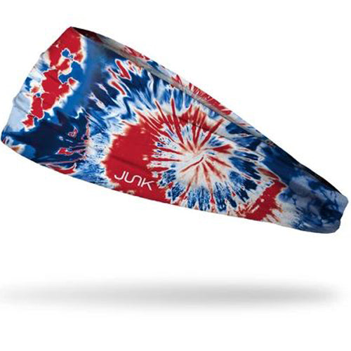 The Junk Pride Headband by Junk features a blue, red, and white tie-dye design, sweat-wicking technical t-shirt fabric, "JUNK" logo print, and is shown against a white background.