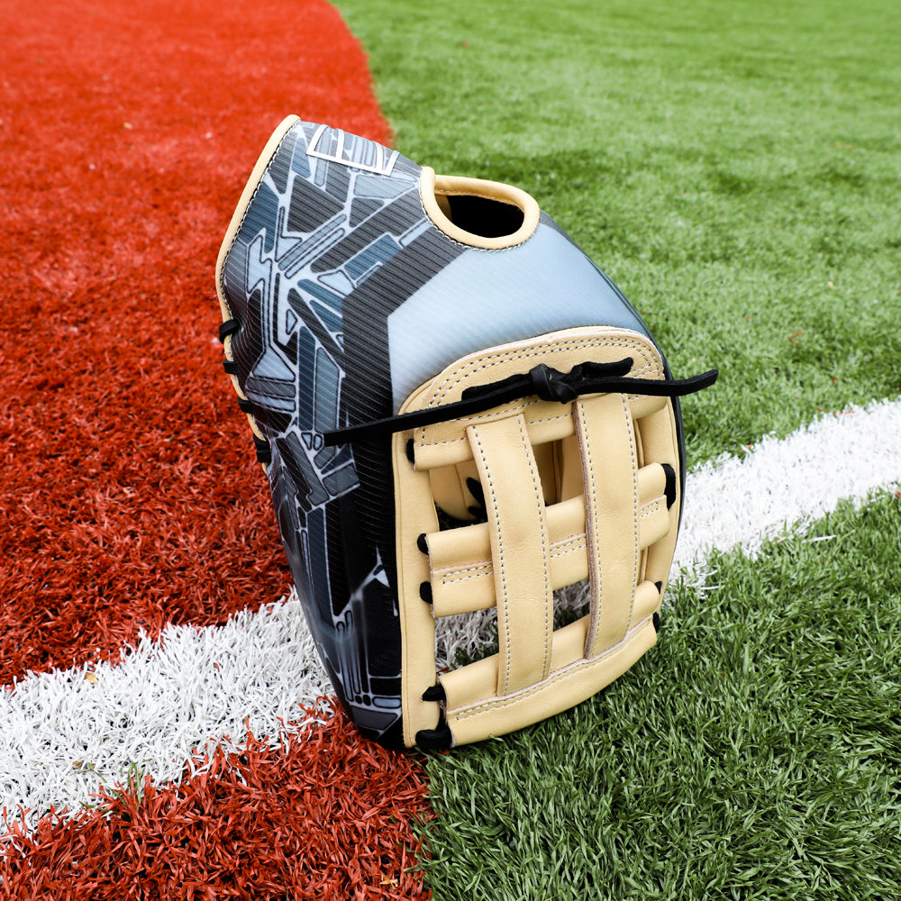 A Rawlings REV1X 12.75" Baseball Glove (REV3039-6) in tan and black with a geometric pattern stands upright on artificial turf, right where the red and white sections of the field meet.
