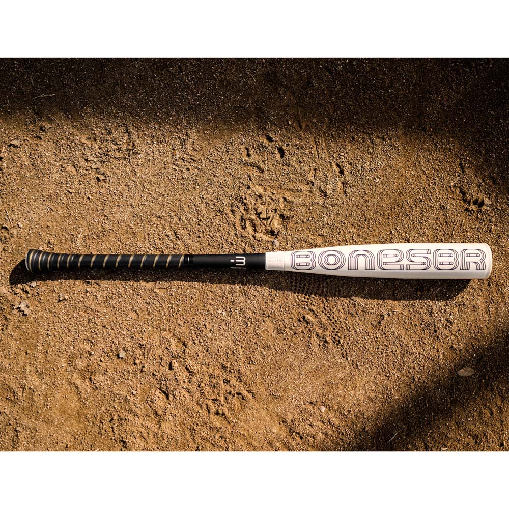 A Warstic 2024 Bonesaber Hybrid (-3) BBCOR Baseball Bat rests on the ground, ready for the next big hit.