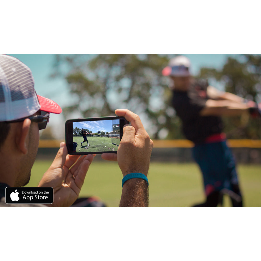 Someone uses the Pocket Radar Smart Coach Radar: SR1100 by Pocket Radar to record a baseball player swinging a bat on the field via the app. The screen displays the batter in action, with the App Store logo in the bottom left corner.