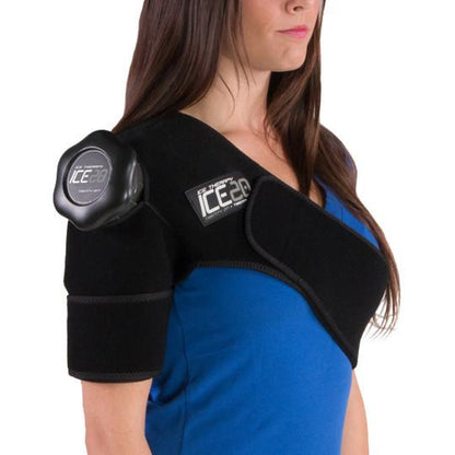 A woman in a blue shirt wears a Bownet ICE20 Single Shoulder Ice Compression Wrap (ICE-Shoulder) with a refillable ice bag on her upper arm and shoulder, secured by Velcro straps for targeted neoprene therapy.