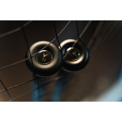 Two black hockey pucks rest on netted strings, one marked with gold 33 in soft light—echoing the poised power of the 2022 Victus Vandal 2 (-8) USSSA Baseball Bat: VSBV2X8 from Victus, ready for its next big hit.