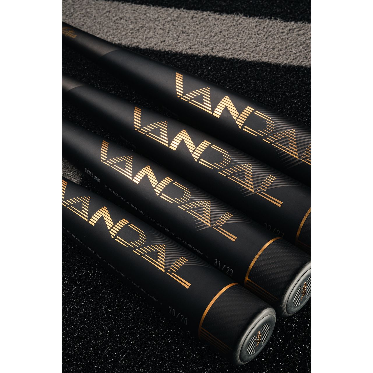 Three 2022 Victus Vandal 2 (-8) USSSA baseball bats from Victus, featuring "VANDAL" in gold, are lined up on a black and gray textured surface with their handles pointing away and barrels together in the foreground.