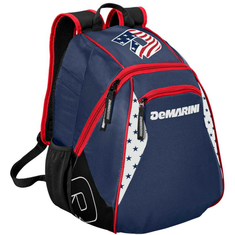 The DeMarini Voodoo Junior Backpack (WTD9106) features navy blue with red zippers, black bottom, white side panels with blue stars, an American flag patch on top, and red-trimmed padded shoulder straps. Ideal for young baseball players.