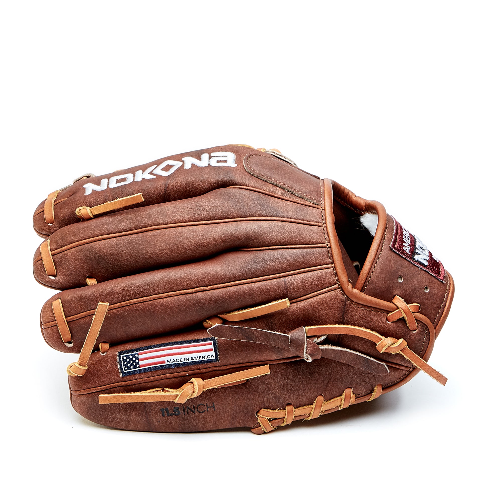 The Nokona Walnut 11.5" Baseball Glove (W-1150) features brown Walnut Crunch leather, tan laces, NOKONA branding on the back, an American flag patch, and "11.5 INCH" by the thumb. Shown closed against a white background.