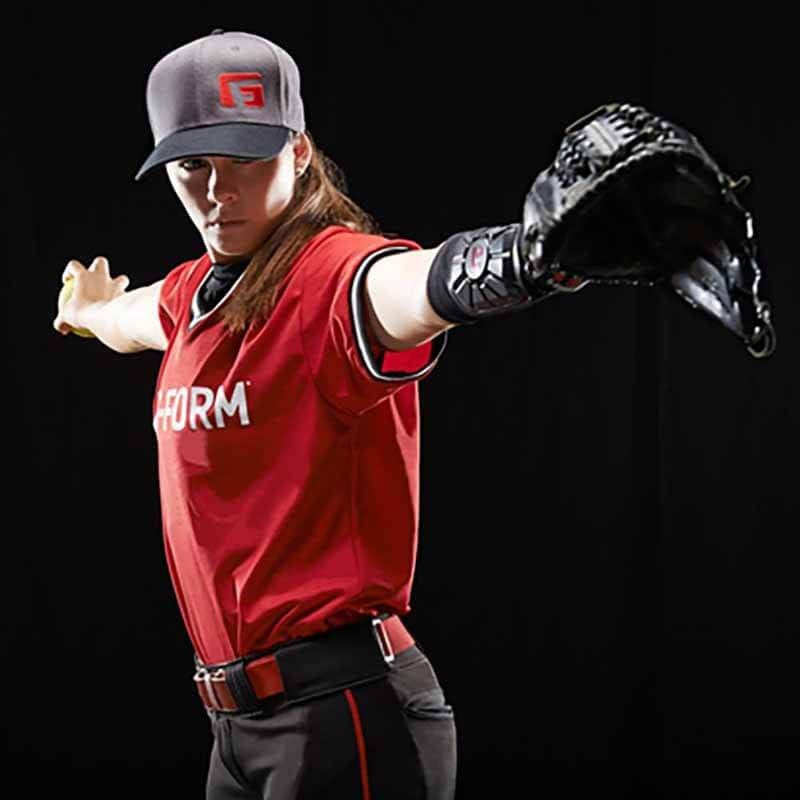 A woman in a baseball uniform and glove wears the G-Form Pro Wrist Guard (WG0102) by G-Form, featuring SmartFlex pads for impact protection.