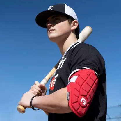 A young baseball player in a black uniform and cap holds a bat over his shoulder, confidently wearing the G-Form Elite Speed Batter's Elbow Guard: EP15 with SmartFlex padding, as he looks into the distance against a clear blue sky.