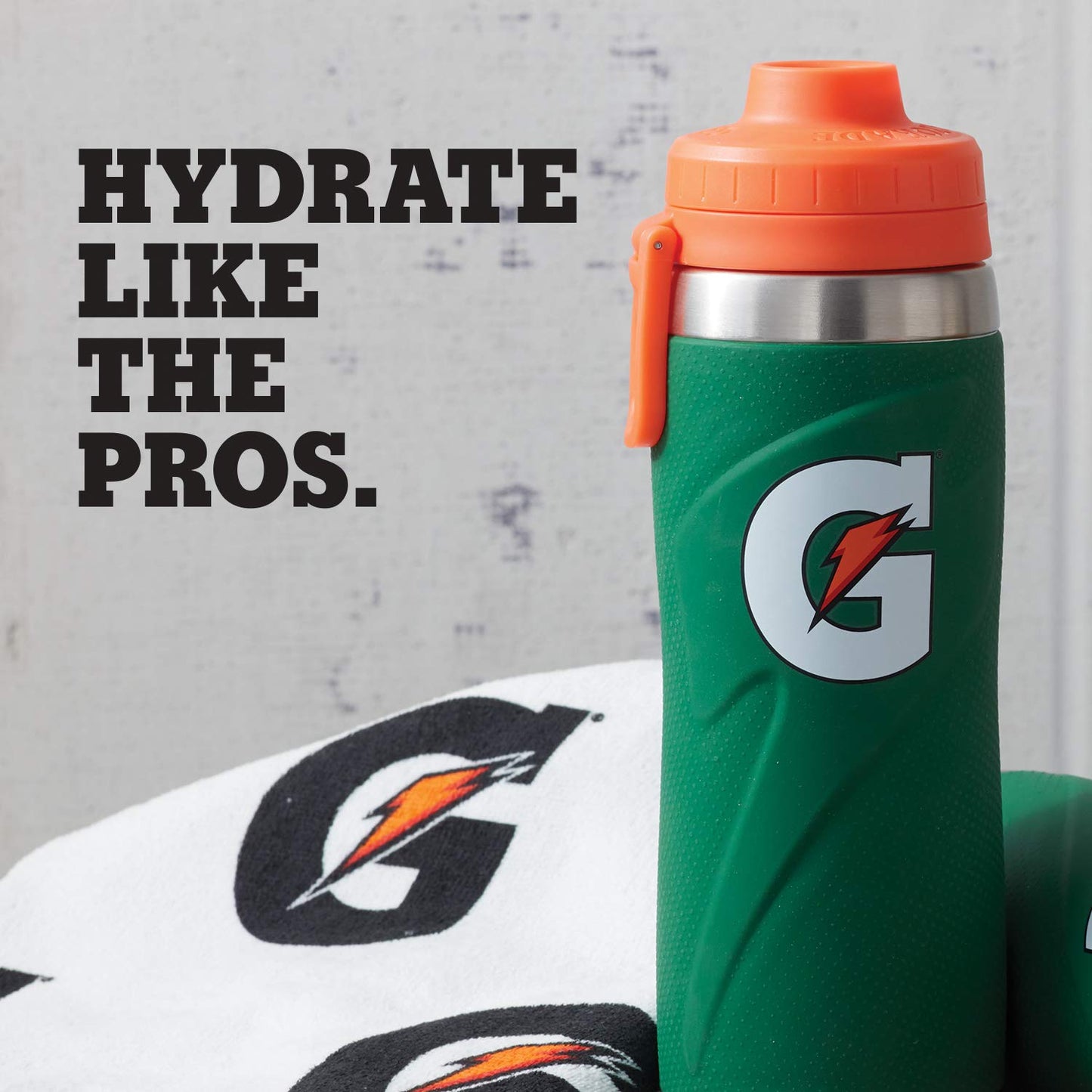 A green Gatorade 26 oz Stainless Steel Water Bottle (43669) with an orange lid stands beside a white towel with the Gatorade logo. Text on the left reads, HYDRATE LIKE THE PROS.