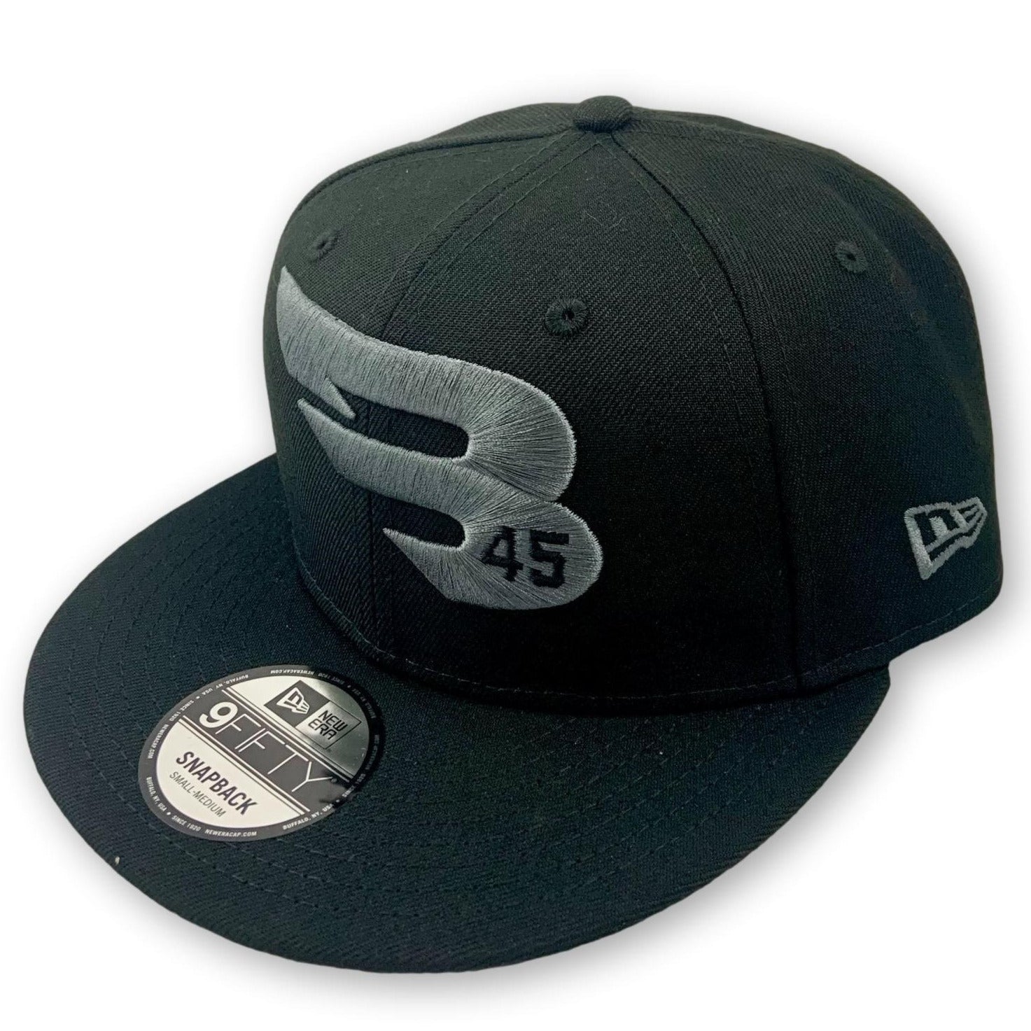 The B45 Black 9FIFTY New Era Snapback Hat Charcoal Logo Edition (950-GREY-BLACK) features a large silver B and 45 on the front, a New Era logo on the side, flat brim with sticker, and an adjustable fit.