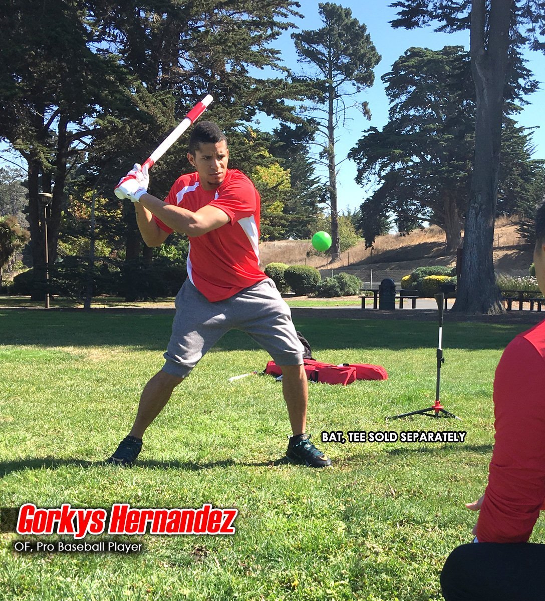 A man in a red shirt and gray shorts gets ready to hit a green PowerNet 2.8" Weighted Hitting and Batting Progressive Training Ball (9 Pack) on a grassy field. Text: Gorkys Hernandez, OF, Pro Baseball Player. Bat, tee sold separately.