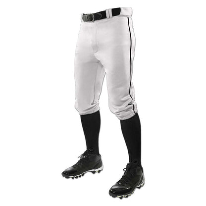 A person wearing Champro Sports Youth Triple Crown Knicker Baseball Pants with Piping (BP101Y), featuring black piping, and paired with a black belt, black knee-high socks, and black cleats stands against a white background.